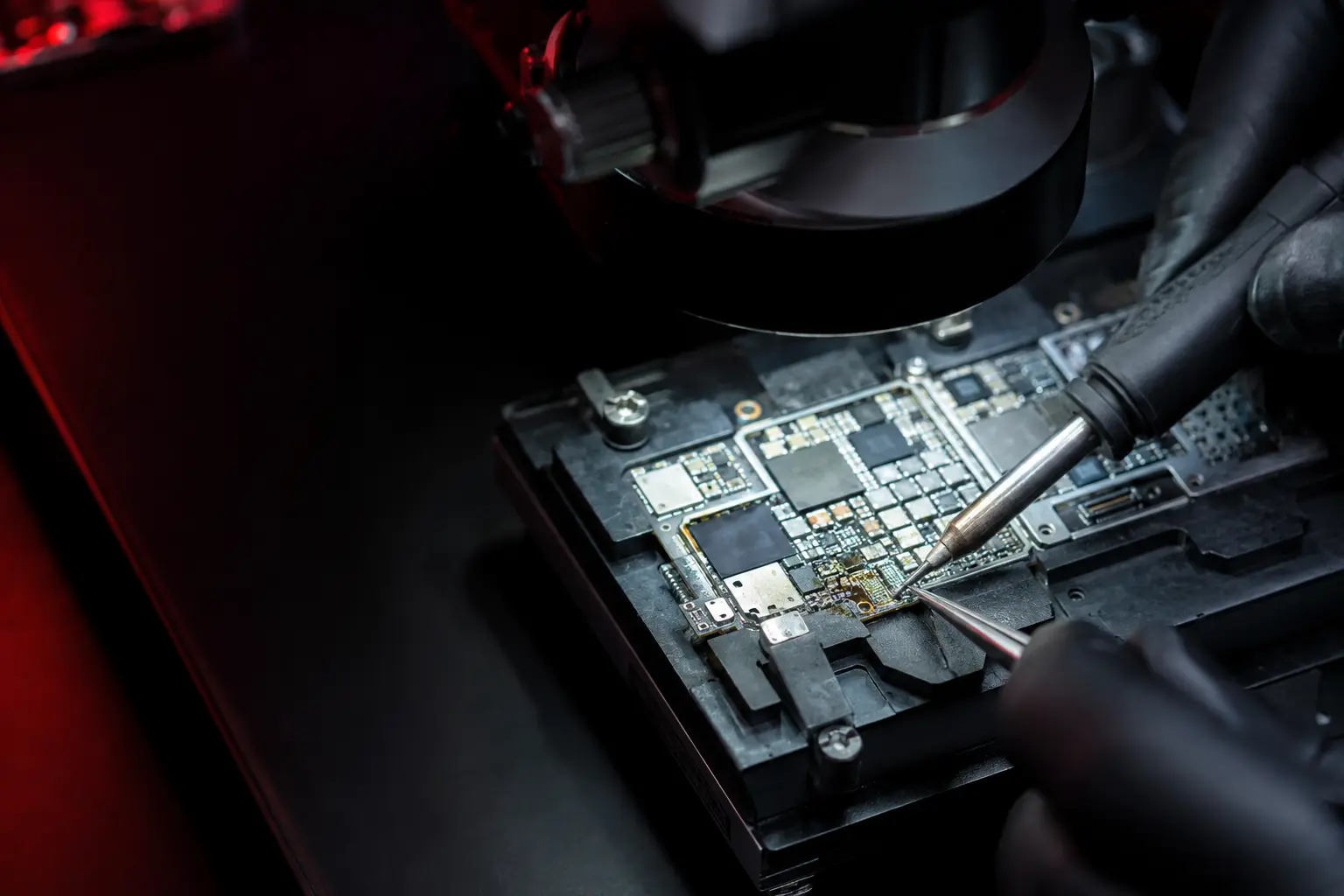 Microsoldadura de precisión en la placa de un celular bajo microscopio